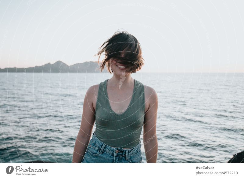 Eine junge Frau geht auf dem Pfad der Felsen am Ufer und blickt auf das abendliche Meer.Junge Hipster-Mädchen macht einige Wanderungen am Ufer, Reisen und Low-Budget-Reisekonzepte, Kopie Raum