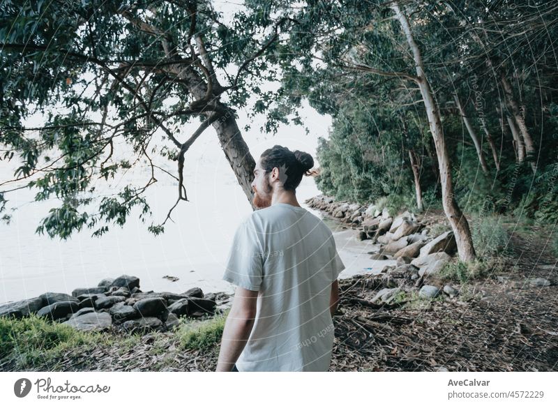 Ein junger moderner Mann geht auf dem Pfad der Felsen am Ufer und schaut auf das abendliche Meer.junges Hipster-Mädchen macht einige Wanderungen am Ufer, Reisen und Low-Budget-Reisekonzepte, Kopie Raum