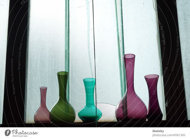 Bunte gefärbte Vasen und Kolben aus Glas im Regal vor der Fensterscheibe eines alten Fabrikgebäude im Stadtviertel Margaretenhütte in Gießen an der Lahn in Hessen