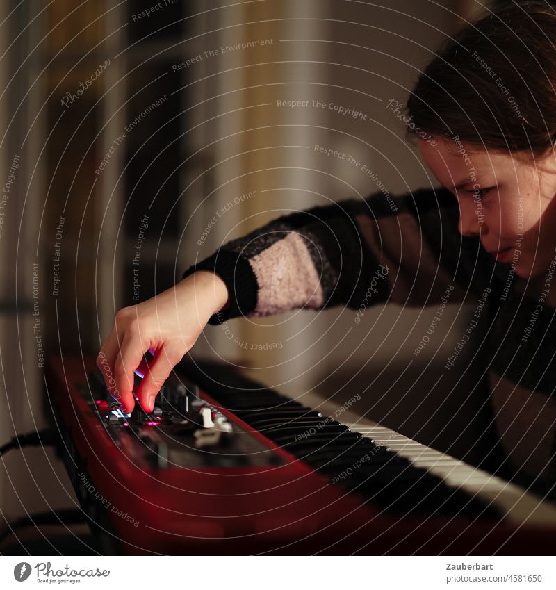 Mädchen spielt nachts auf rotem Keyboard, Hand am Regler Hände songwriting Tastatur Tasten Knöpfe Musik spielen Musik machen Musikinstrument Nahaufnahme