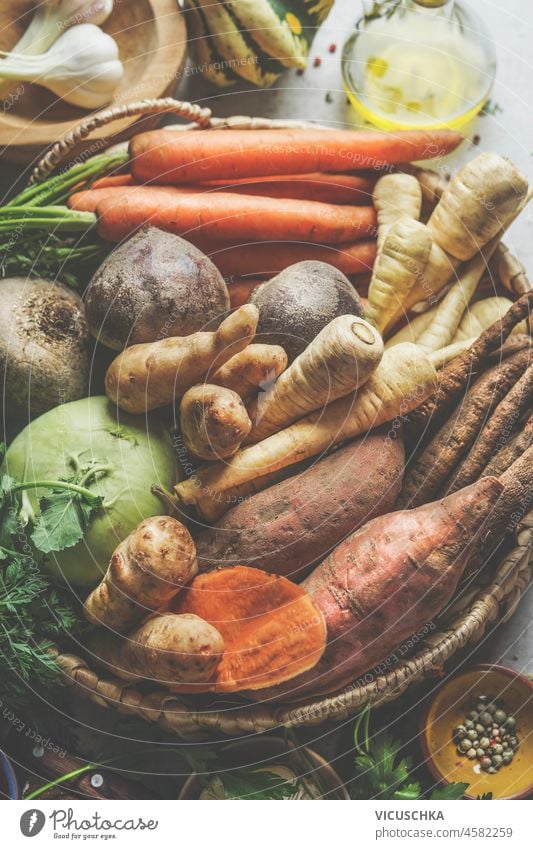 Nahaufnahme von verschiedenen rohen Bio-Wurzelgemüsen: Pastinake, Süßkartoffel, Karotten, Kohlrabi und Topinambur auf einem geflochtenen Tablett. Gesunder, nachhaltiger Lebensstil. Plastikfreier Haushalt. Ansicht von oben