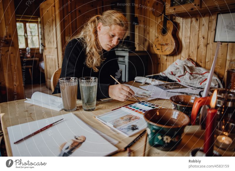 junge Frau malt mit Watercolor in einer urigen Hütte malen Pinsel Farbe Aquarell Motiv kreativ zeichnen Kreativwerkstatt Atelier gemütlich Ideen Papier