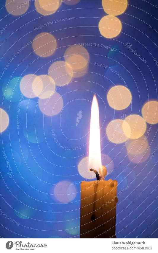 Einsam brennende Kerze vor blauem Hintergrund mit  schönem Bokeh Kerzenschein Kerzenlicht Docht Flamme advent 1. Advent Gemütlichkeit behaglich Behaglichkeit