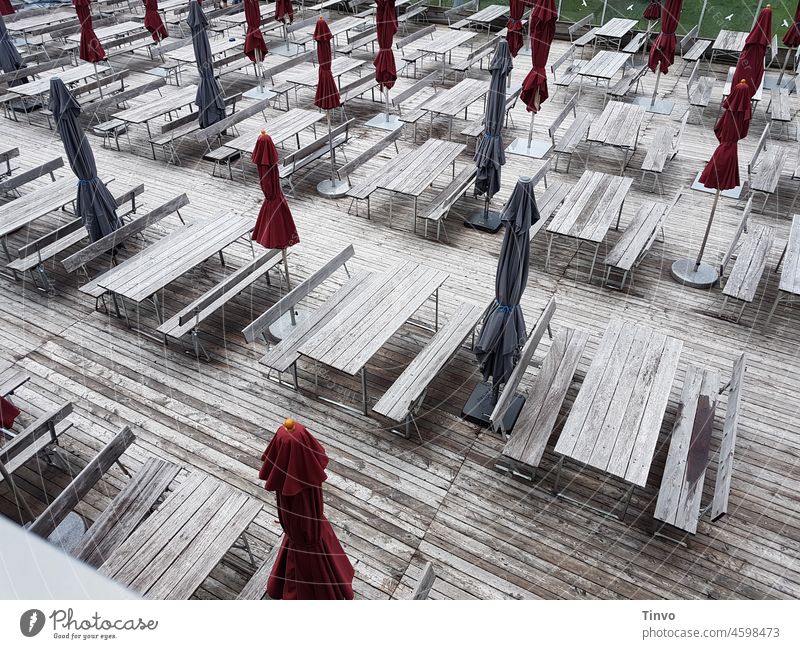 Menschenleere Gastronomie-Terrasse aus Holz mit geschlossenen roten und blauen Sonnenschirmen Außengastronomie Holzterrasse menschenleer grau Vogelperspektive