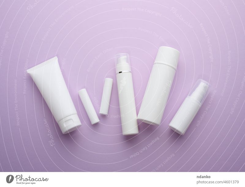 Flasche und leere weiße Plastiktuben für Kosmetika auf einem lila Hintergrund. Verpackung für Creme, Gel, Serum, Werbung und Produktförderung purpur Schönheit