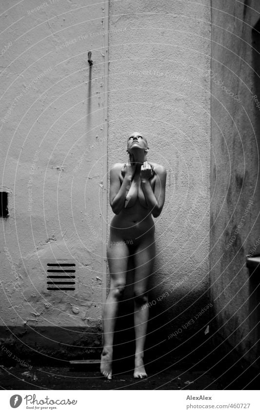 nackte Frau steht im Innenhof und schaut erstarrt nach oben ins Licht Junge Frau Jugendliche Körper Frauenbrust Beine Fuß 18-30 Jahre Erwachsene Wand