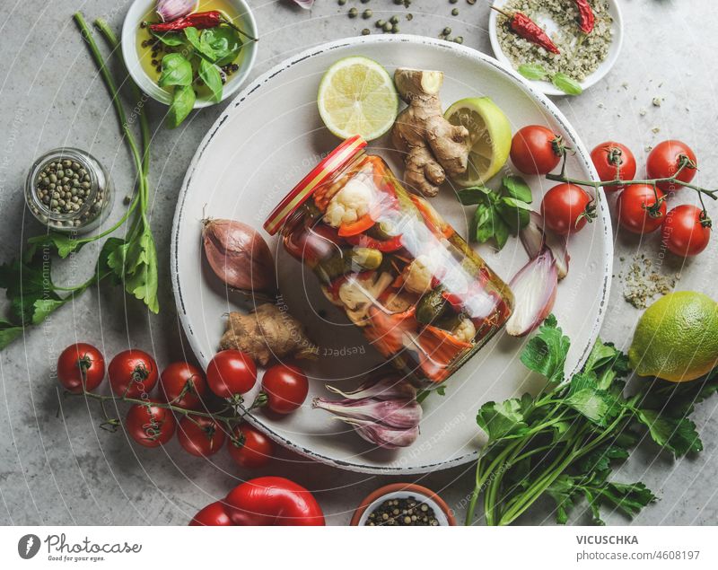 Glas mit verschiedenen eingelegten Gemüsesorten auf Teller mit Kräutern und Gewürzen zum Einlegen, Einmachen oder Fermentieren. Ansicht von oben. Gesunder Lebensstil