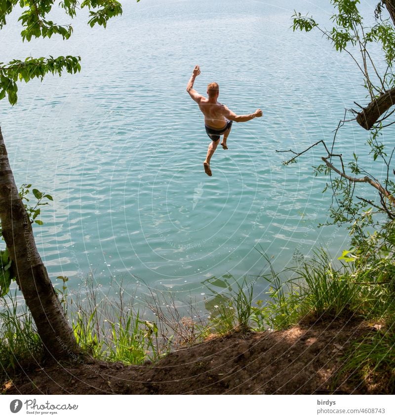 junger Mann im Sprung in einen Badesee bei schönem Wetter See Urlaub zuhause springen Baden Wasser Spaß Sommerurlaub Freizeit Baggersee ins Wasser springen