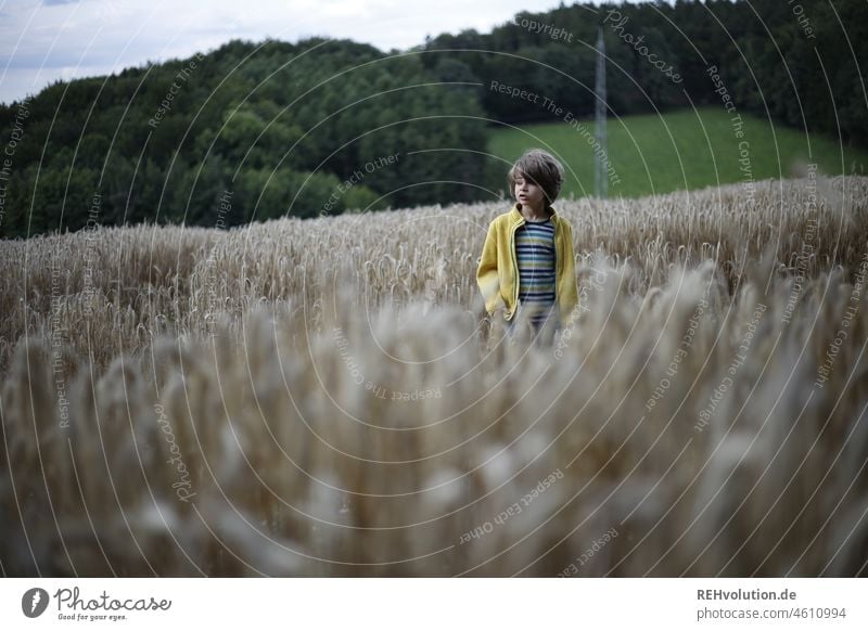 Kind steht in einem Feld Natur Kindheit Umwelt natürlich Mensch Junge Umweltschutz Wiese Außenaufnahme Wolken Himmel bewölkt grauer Himmel bedeckt Wetter