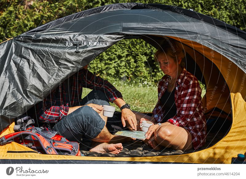 Paar Planung nächste Reise, während mit Karte im Zelt sitzen. Menschen entspannen im Zelt auf dem Campingplatz während des Sommerurlaubs Urlaub Ausflug