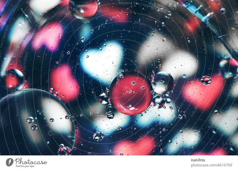 Eine schöne und lebendige Makro von Ölblasen auf dem Wasser mit einer Unschärfe von weißen und rosa Herzen Muster auf schwarzem Hintergrund abstrakt Erdöl