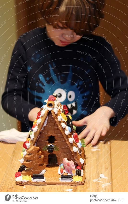 Häuslebauer - Junge hat ein Lebkuchenhaus zusammengebaut und mit Süßigkeiten verziert Kind Schulkind Bonbons Verzierung Dekoratio Kreativität kreativ Handarbeit