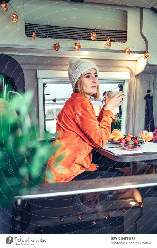 Frau beim Frühstück in einem Wohnmobil Kleintransporter nachdenklich Beteiligung Tasse Kaffee Morgen Brötchen zur Seite schauend schön hübsch besinnlich Essen