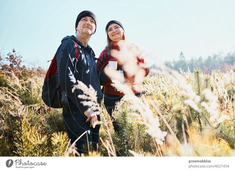 Paar genießt die Natur während der Urlaubsreise. Wanderer mit Rucksäcken Blick auf die Berge zu sehen. Menschen stehen in hohem Gras auf dem Weg zu den Bergen an einem sonnigen Tag