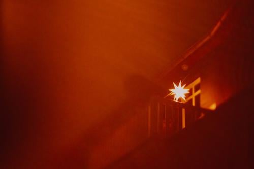 leuchtender Adventsstern auf Balkon Bokeh Experiment Lichter Tilt Unschärfe Herrnhuter Stern Haus Fassade rot Nebel Dunst Weihnachten & Advent