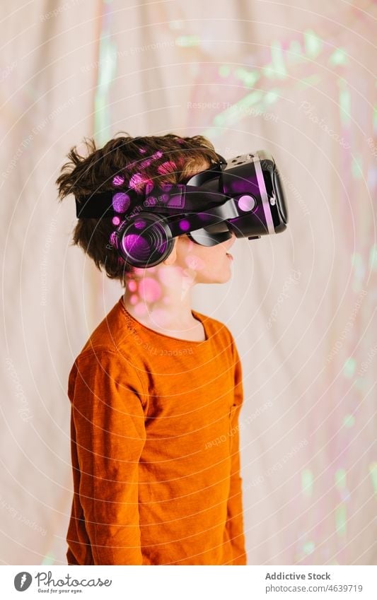 Junge erkundet den Cyberspace mit VR-Brille Kind Virtuelle Realität erkunden Erfahrung Schutzbrille Headset virtuell neonfarbig Apparatur Gerät Innovation