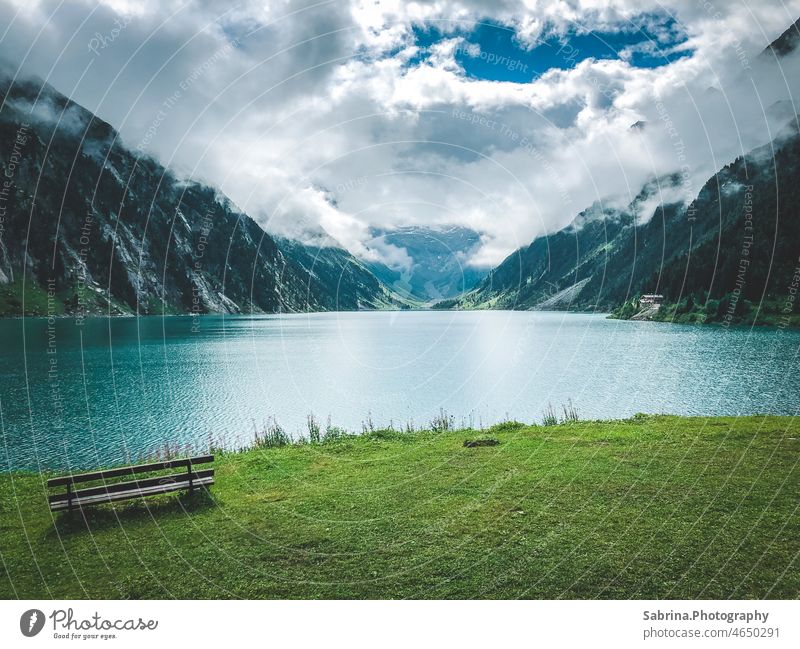 Eine Holzbank vor dem Schlegeisspeicher im Zillertal im Sommer bei Wolken und Sonnenschein im Mix Zillertaler Alpen schlegeisspeicher Schlegeissee Tirol