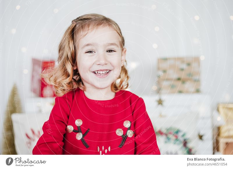 Porträt von glücklichen kleinen Mädchen tragen rote Weihnachtskleid zu Hause über Weihnachtsdekoration. Urlaub Konzept Weihnachten heimwärts Glück Kind