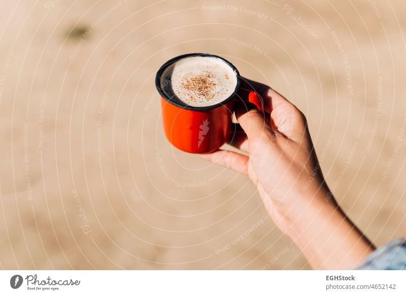 Die Hand einer Frau hält eine rote Emaille-Tasse mit Kaffee, Zimt und Kakao Erwachsener Herbst herbstlich Hintergrund Pause Kaffeetasse Komfort bequem gemütlich