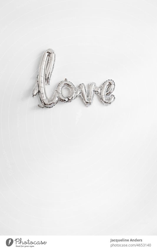 Schriftzug Love als silberner Ballon an der Wand Liebe Valentinstag valentinsgruß Valentinshintergrund valentine valentines day Wort Buchstaben Verliebt