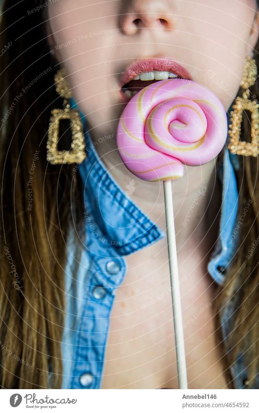 Porträt eines schönen Mädchens mit bunten rosa Twirl Lollipop harte Süßigkeiten auf blauem Hintergrund, Süßigkeiten, Zucker und ungesunde Lebensmittel Konzept