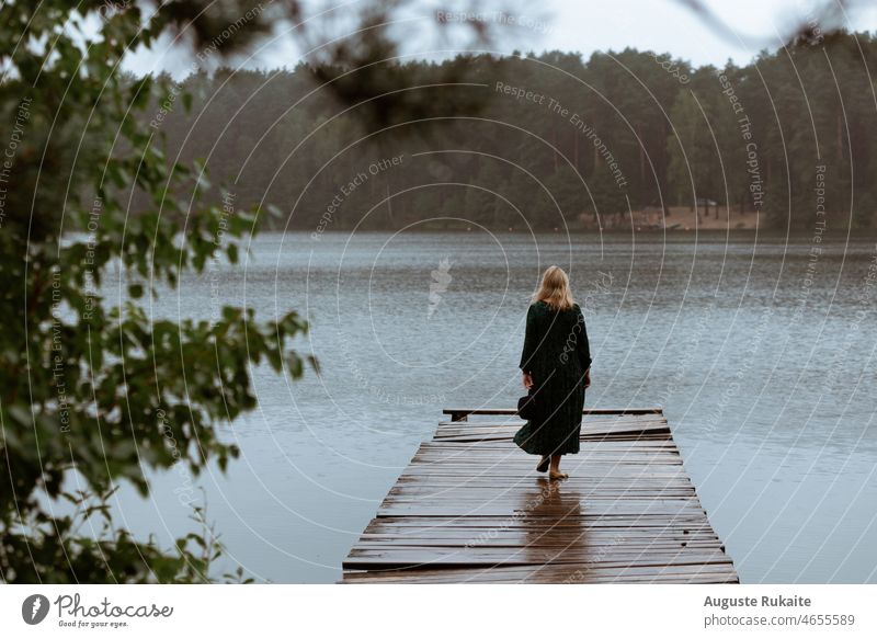 Frau auf einer Brücke in der Nähe des Sees an einem regnerischen Tag Regen nass Regenjacke Wasser schlechtes Wetter Herbst Wassertropfen Natur Tropfen