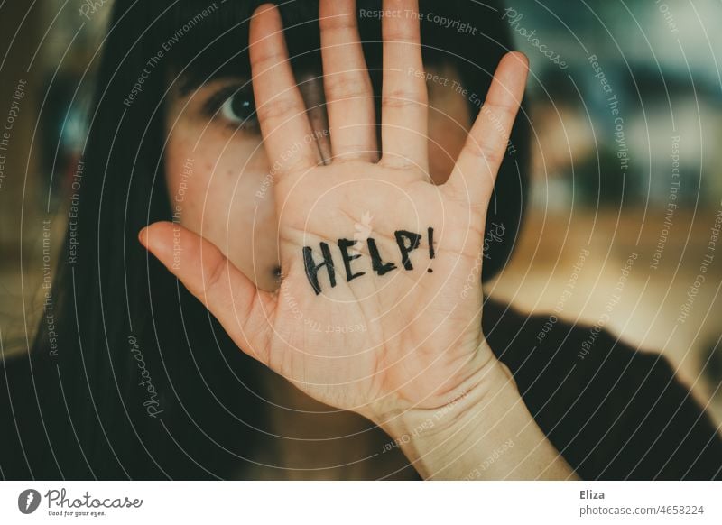 Junge Frau hält sich abwehrend eine Hand vors Gesicht auf dem das Wort Help geschrieben steht Hilfe um Hilfe bitten hilflos Hilfesuchend häusliche Gewalt Angst