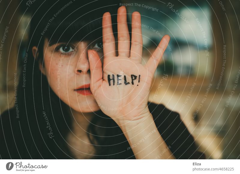 Junge Frau hält sich abwehrend eine Hand vors Gesicht auf dem das Wort Help geschrieben steht Hilfe um Hilfe bitten hilflos Hilfesuchend häusliche Gewalt Angst