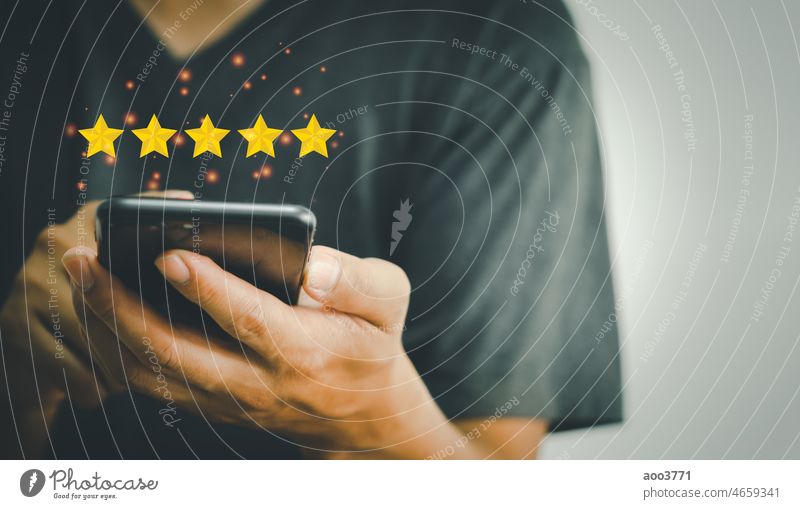 Eine Hand, die ein Telefon benutzt und 5 Sterne auf den Händen hält - ein Konzept zur Bewertung der Kundenzufriedenheit und der Marketingumfrage Feedback