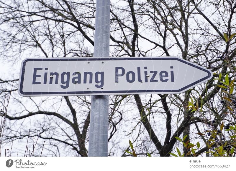 Schild / Wegweiser - Eingang Polizei - an einem Metallrohr vor kahlen Bäumen Hinweisschild Polizeidienststelle Dienststelle Landespolizei Politeia