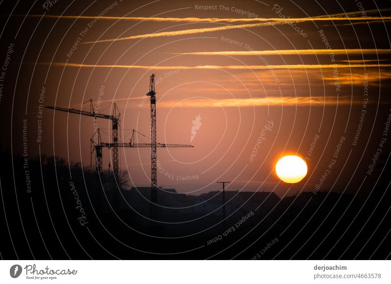 Die Baukräne stehen still , und die  Abendsonne verschwindet gleich am Horizont. Sonnenuntergang Natur Abenddämmerung Landschaft Außenaufnahme Farbfoto