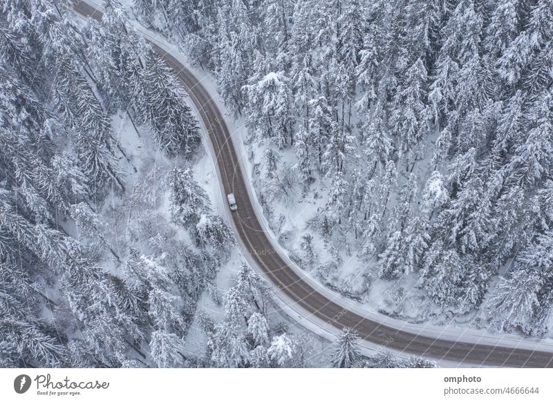 Verschneite kurvenreiche Bergstraße mit fahrendem Auto bei Schneefall Landschaft Antenne Winter Wald Kiefern Straße biegend geschlängelt PKW Lastwagen
