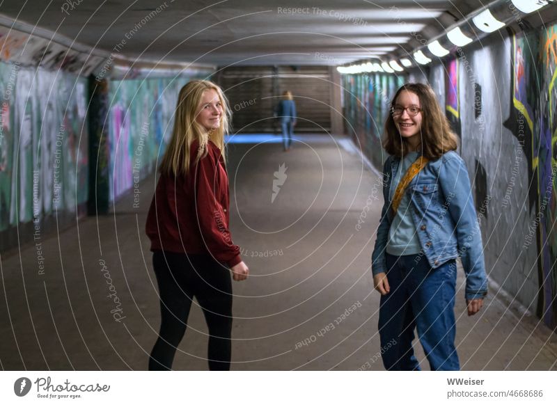 Zwei Mädchen laufen durch einen Fußgängertunnel und sehen sich kurz lachend um Tunnel fröhlich zwei zu zweit Freundinnen Spaß Freude unetrwegs spazieren gehen