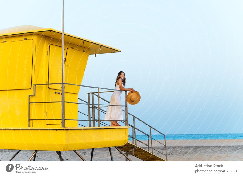 Frau steht in der Nähe der Rettungsschwimmerhütte Strand Ufer allein nachdenken reisen Sand Küste gelb Turm Gebäude MEER beobachten Meeresufer Seeküste Kabine