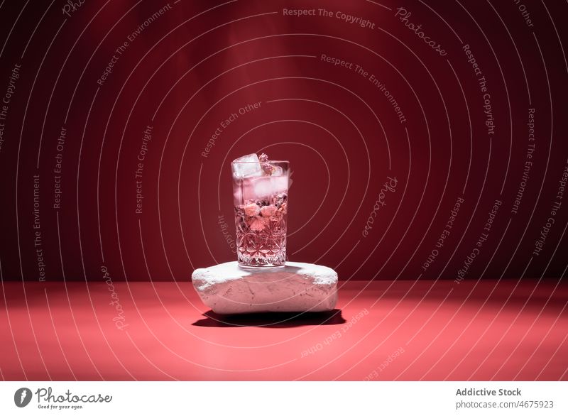 Gin Tonic mit Eis auf rotem Hintergrund Cocktail rosa Alkohol Getränk Schnaps Glas Aperitif Atelier kalt Würfel trinken Erfrischung gefroren liquide Bestandteil