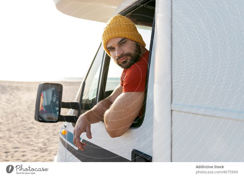 Hipster sitzt im Wohnwagen am Strand im Sommer Mann Wohnmobil reisen Kleintransporter Sonnenuntergang Reisender Anhänger männlich Urlaub Seeküste geparkt