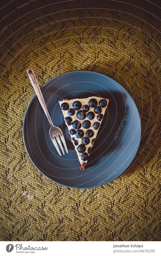 Heidelbeer Kuchenstück mit Tortengabel auf dem Teller auf dem Sofa Blaubeeren Heidelbeeren Obst Beeren blau gesund Antioxidantien Vitamine Lebensmittel lecker