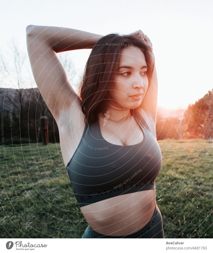 Porträt einer jungen Frau, die ihre Arme während einer Trainingseinheit ausstreckt, um bei einem Sonnenuntergang Gewicht zu verlieren. Training neues Sportkonzept.