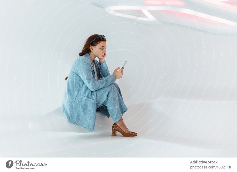 Frau surft auf dem Smartphone im Studio Browsen soziale Netzwerke Atelier modern Design Internet online Stil Apparatur benutzend Gerät Telefon elegant blättern