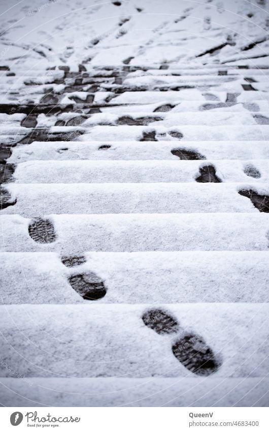 Treppe mit Schnee und Fußspuren Treppenstufen Richtung Verkehr laufen Winter hochlaufen Treppen steigen Schuhsole Spuren Weg hinauslaufen Schwarzweißfoto