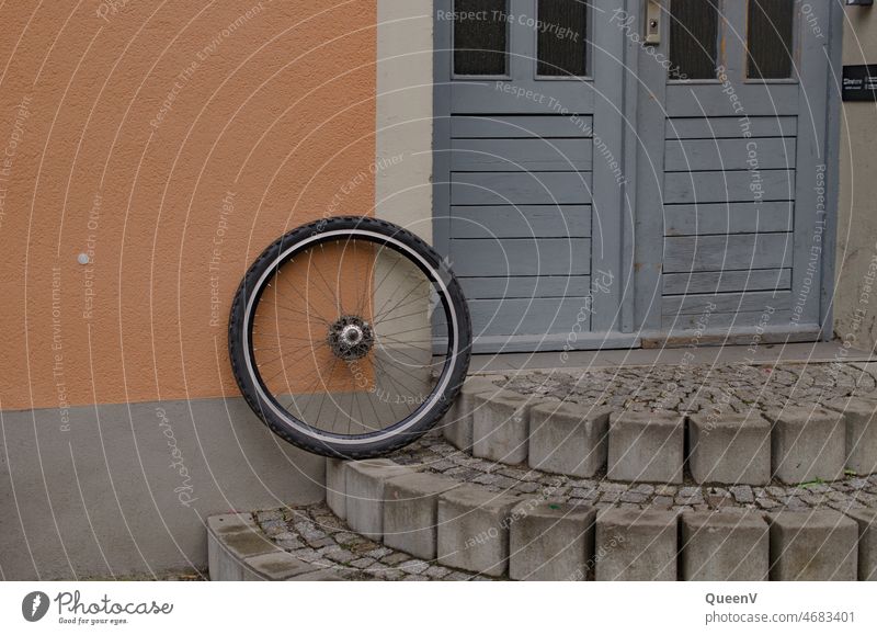Fahrrad Reifen mit blauer Tür und lachsfarbiger Fassade Fahrradfahren Verkehrsmittel Mobilität Fahrradreifen Rad Speichen Reparatur Freizeit & Hobby rund parken