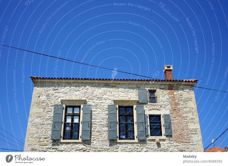 Altes Haus mit Fassade aus Naturstein in Naturfarben vor blauem Himmel im Sommer bei Sonnenschein in Foca bei Izmir am Ägäischen Meer in der Provinz Izmir in der Türkei