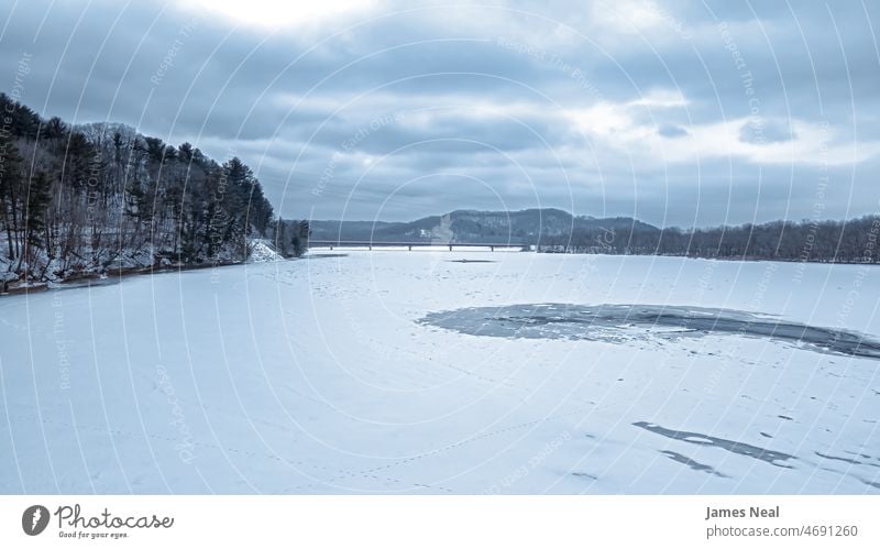 Ein düsterer Tag auf dem eisigen Fluss Ruhe Brücke Natur Wasser Frost Schönheit See Hügel Schnee Straße Baum Wisconsin Temperatur im Freien Umwelt dramatisch