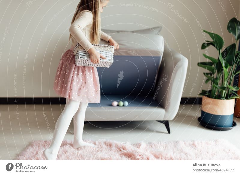 glückliches kaukasisches Kleinkind, acht Jahre alt, zu Hause im Wohnzimmer mit bunten Ostereiern. Während der Coronavirus-Covid-19-Pandemie zu Hause bleiben