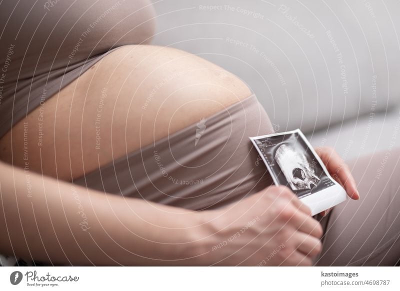 Schwangere Frau Bauch. Schwangerschaft Konzept. Schwangere Bauch Nahaufnahme. Detail der schwangeren Frau hält Ultraschall-Foto von ihrem Embryo Kind. Liebe