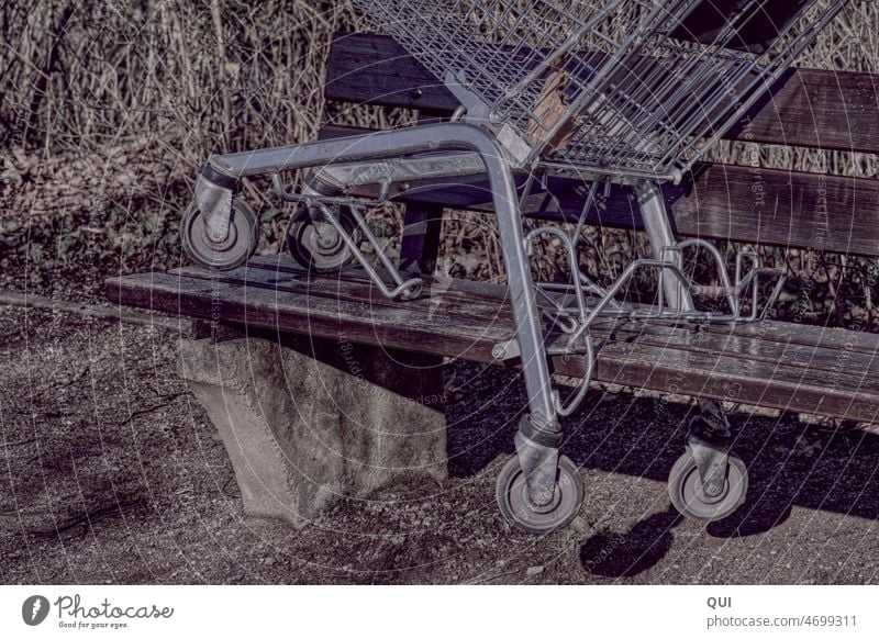 Zurückgelassener Einkaufswagen auf Parkbank Verlassen weggeworfen Metallwaren Supermarkt Rollen Räder Umwelt Achtlosigkeit grau Strukturen & Formen Konsum