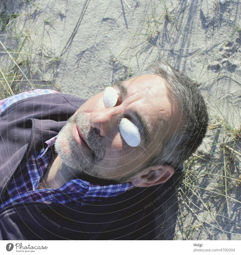 Frühlingssonne genießen - Porträt eines Senioren, der auf dem Sand in der Sonne liegt Mensch Mann Kopf Sonnenschutz Muschel Strand Sonnenschein Sonnenlicht