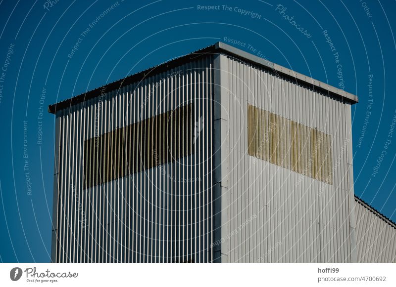 Wellblechfassade einer Lagerhalle Wellblechwand Industrieanlage Blauer Hintergrund Architektur Hochhaus Modern monoton Blauer Himmel blau Fassade