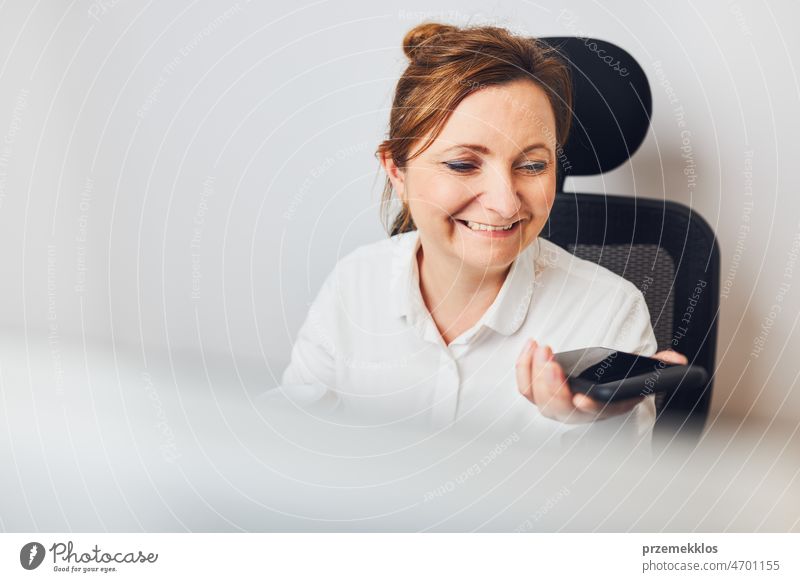 Geschäftsfrau im Gespräch mit einem Mobiltelefon im Lautsprechermodus. Frau, die eine Sprachnachricht mit der Sprachassistenz- und -erkennungsfunktion ihres Smartphones aufnimmt