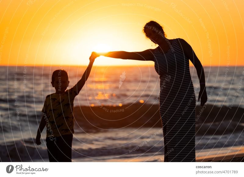 Mutter und Sohn halten sich am Strand bei Sonnenuntergang an den Händen Baby heiter Kind Küste Tochter genießen genießend Familie Frau Spaß Mädchen Hand